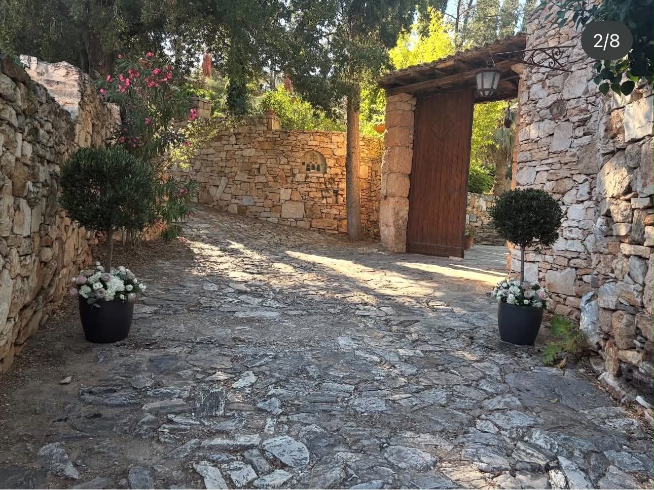 An open wooden gate, stone walls and flower arrangements at Vorres Museum